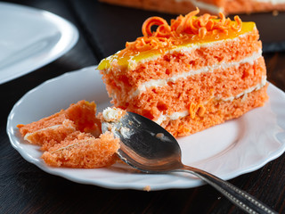 one bitten piece of carrot cake lies on a white plate.