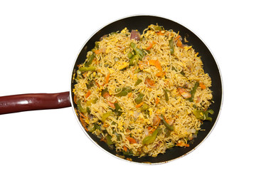 Top view of egg noodles in a non stick frying pan on a white background