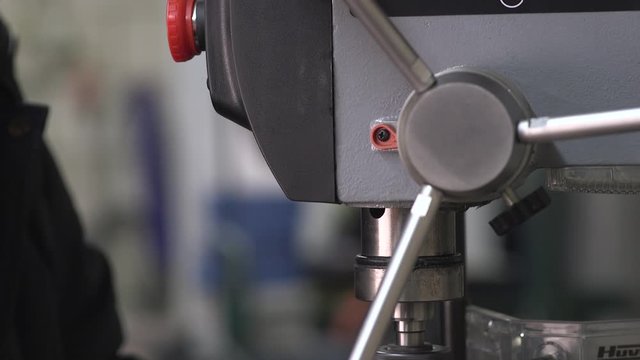 close up shot of hand operating vertical drilling machine with a blurry background