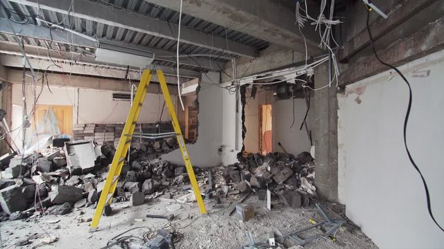 Camera is moving forward, view of demolition work in apartment. The room is full of broken bricks and blocks from broken walls