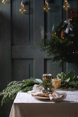 Christmas or New year table setting with empty ceramic plates, napkins, Christmas thuja wreath,...