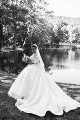 Bride holding a bouquet of flowers. Beautiful woman. Wedding bouquet in bride's hands. Beautiful bride in white dress in the park. Beautiful woman with professional make up and hair style.