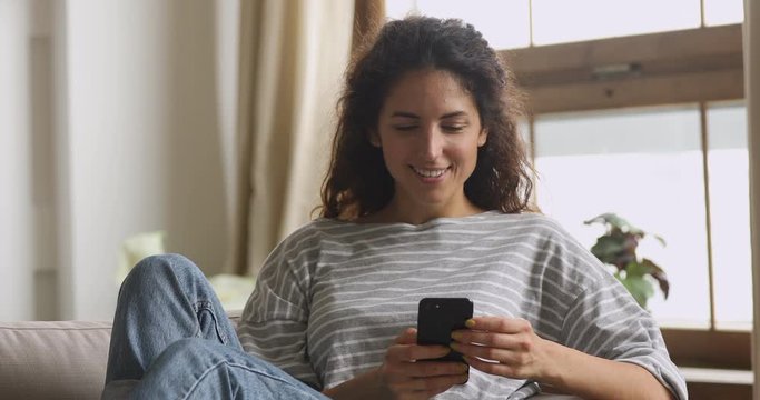 Happy young woman using smart phone apps messaging at home