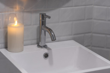 Modern faucet with white ceramic washbasin sink and candle light interior contemporary