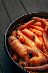 Fresh raw authentic ugly carrots on dark background, harvesting