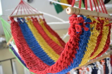 Small hammock made of fabric, wood with striking red, yellow and blue colors with blurred background.