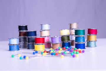 Colorful thread reels with needles and pins in foreground