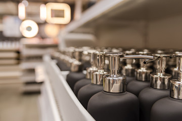 picture of many soap dispenser  in a row ,displayed on shelves in a shop