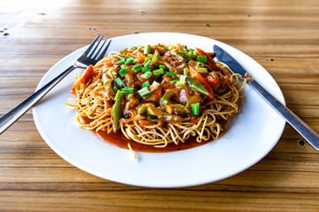 American Chopsuey served in a white plate on wooden surface