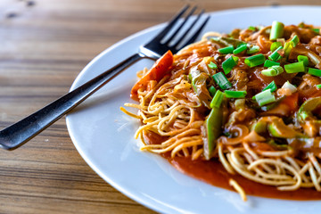 American Chopsuey served in a white plate on wooden surface