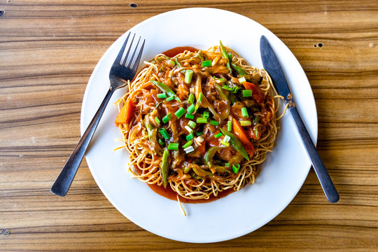 American Chopsuey served in a white plate on wooden surface