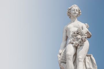Fototapeta na wymiar Ancient top roof statue of sensual Italian Renaissance and Rococo Era naked woman in Potsdam at blue sky, Germany