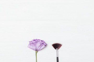 Fan makeup brush next to fresh flower