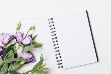 Top view blank notebook next to bouquet