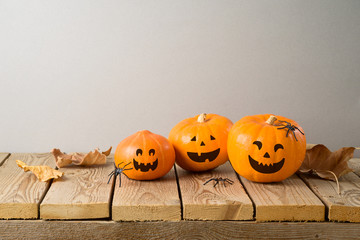 Halloween holiday concept with jack o lantern pumpkin and autumn leaves on wooden table
