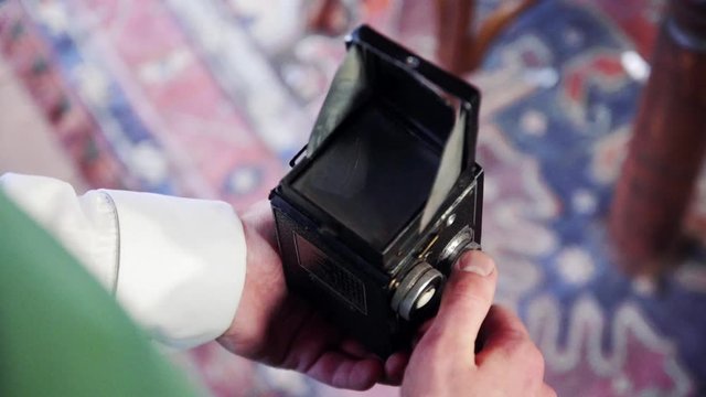 Elf photographing. Retro camera in man's hands. Elf is setting up retro camera. Close-up.