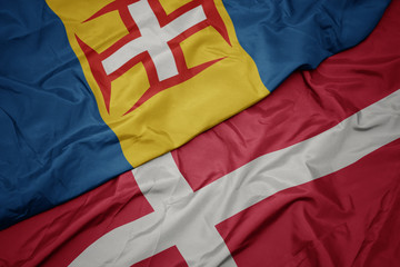 waving colorful flag of denmark and national flag of madeira.