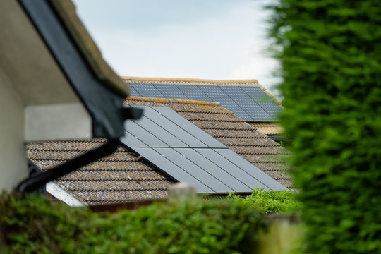 Isolated, Shallow Focus Of Newly Installed Solar Panels On A Detached House. Also In View Is Another House With Solar Panels Installed To Help Reduce Electric Utility Bills.