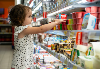 Little girl buying yogurt in supermarket. Child in supermarket select products - 296962933