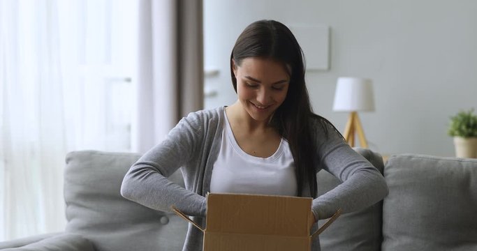 Satisfied female customer open parcel box sit on sofa