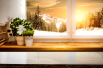 Blurred snowy winter sunshine landscape outside the window kitchen  with table top for products and decorations.