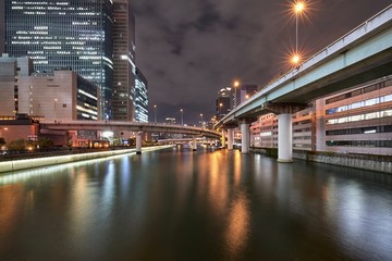 Fototapeta na wymiar Osaka night scene, urban expressway bridges over the river in downtown Osaka, Japan