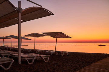 Empty beach equipped with sunshades and sunbeds before dawn