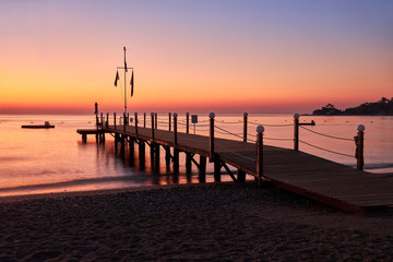 Fototapeta na wymiar Sea dawn overlooking a large wooden pier and swimming pontoon.