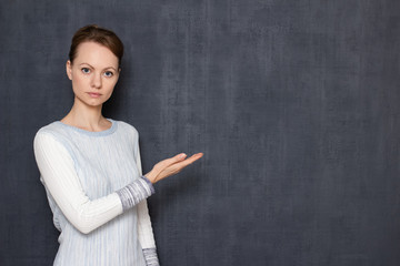 Portrait of serious woman pointing at copy space on right