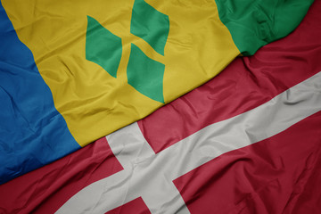 waving colorful flag of denmark and national flag of saint vincent and the grenadines.