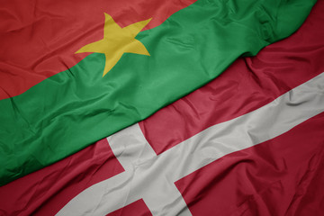 waving colorful flag of denmark and national flag of burkina faso.