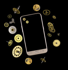 The smartphone is surrounded by various parts and gears of mechanisms of golden and silver colors