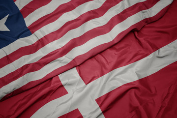 waving colorful flag of denmark and national flag of liberia.