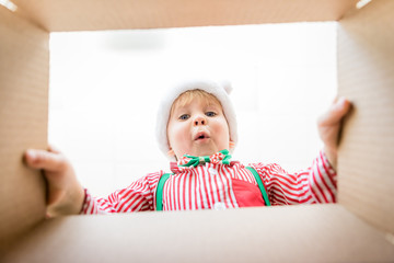 Surprised child unpack Christmas gift box - obrazy, fototapety, plakaty