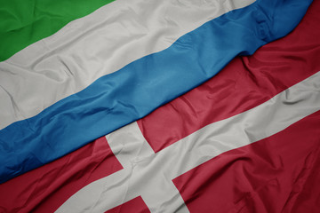 waving colorful flag of denmark and national flag of sierra leone.