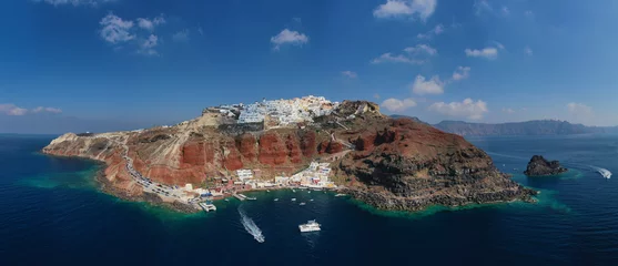 Schilderijen op glas Aerial drone panoramic photo of traditional and picturesque village of Oia in volcanic island of Santorini, Cyclades, Greece © aerial-drone