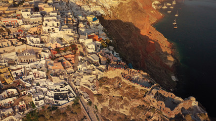 Aerial drone photo of world famous beautiful sunset at traditional and picturesque village of Oia with golden colours, Santorini island, Cyclades, Greece