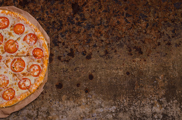 Pizza with cheese and tomatoes with copy space on an unusual brutal metal background with rust. For menus and advertising pizzerias