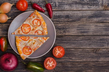 Sliced ​​pizza with cheese and tomatoes on a gray plate with ingredients on a dark wooden background with copy space. For menus and advertising pizzerias