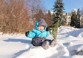 Fototapeta na wymiar A small child sits in the snow at park