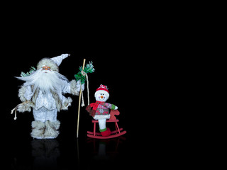 Silver and white Santa and snowman figurines with reflection, shadow isolated on black background for Christmas greeting card design, copy space