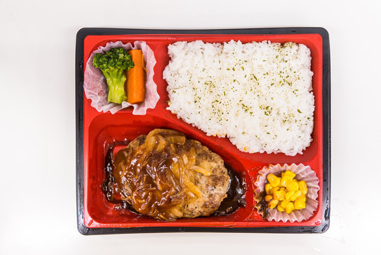 A Japanese Bento Box with rice, vegetables, and teriyaki chicken. Bento boxes are sale in convenience store and train..Japanese food from top view, selected on white background.