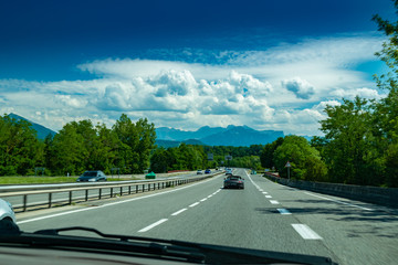 View of the road with cars, signposts and Alps mountains on the road towards the town of Annecy.Haute-Savoie in France.