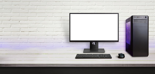 Modern gaming computer on desk. Isolated screen for mockup. Copy space beside on brick wall.