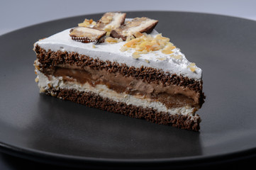 delicious cake with chocolate cream on a black plate