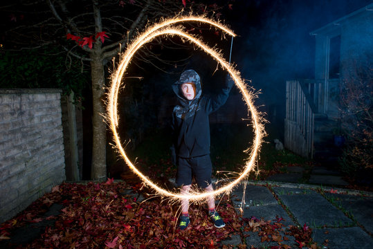 6-7 year old boy making circle, letter O or 0 with sparkler.