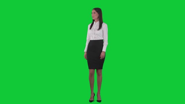Surprised and amazed young woman looking around and up examining. Full body isolated on green screen chroma key background