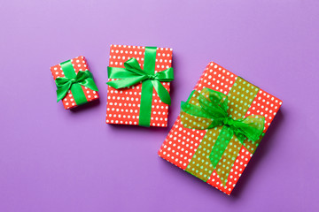 wrapped Christmas or other holiday handmade present in paper with green ribbon on purple...