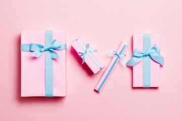 wrapped Christmas or other holiday handmade present in paper with blue ribbon on pink background. Present box, decoration of gift on colored table, top view