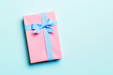 Gift box with blue bow for Christmas or New Year day on blue background, top view with copy space